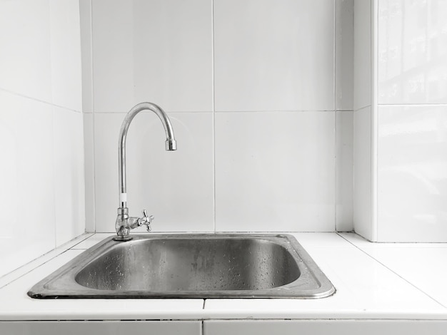 Évier et robinet en acier inoxydable sur carrelage blanc, chambre moderne