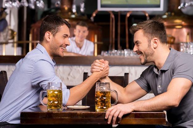 Vieux amis. Deux jeunes hommes joyeux buvant de la bière et s'amusant au bar