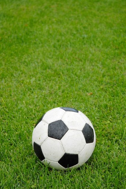 Vieux ballon de football sur l&#39;herbe mouillée