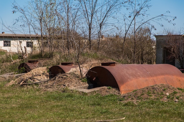 De vieux barils rouillés abandonnés sont à moitié enterrés dans le sol