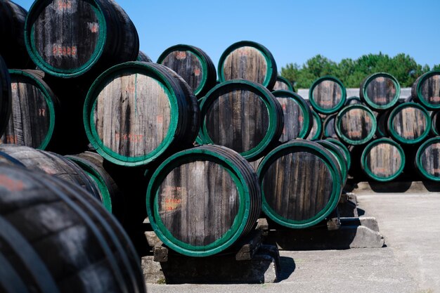 Photo de vieux barils de vin en bois empilés à l'extérieur dans la cour d'une cave.