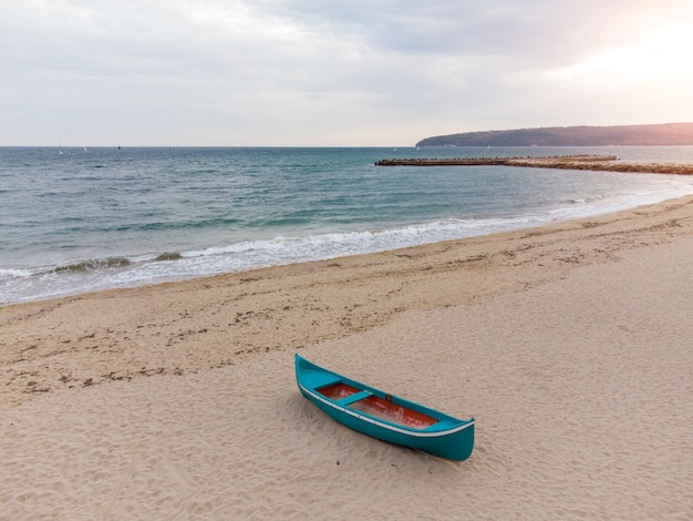 Vieux bateau en bois rose bleu sur la plage de sable