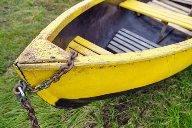 Un vieux bateau en bois vert enchaîné sur la rive du lac en été