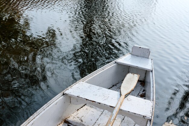 Vieux bateau à rames de couleur blanche sur une surface d'eau.