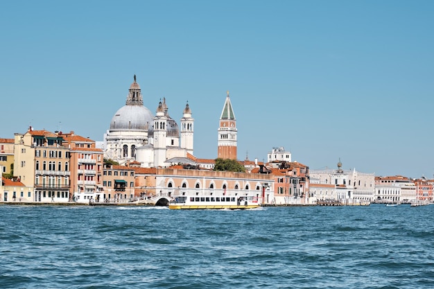 Vieux bâtiments sur la promenade de Dorsodouro, coupole de l'église Santa Maria della Salute, la tour Campanile Saint-Marc à Venise, Italie. Architecture vénitienne traditionnelle et bateau à passagers, vue depuis le lagon.