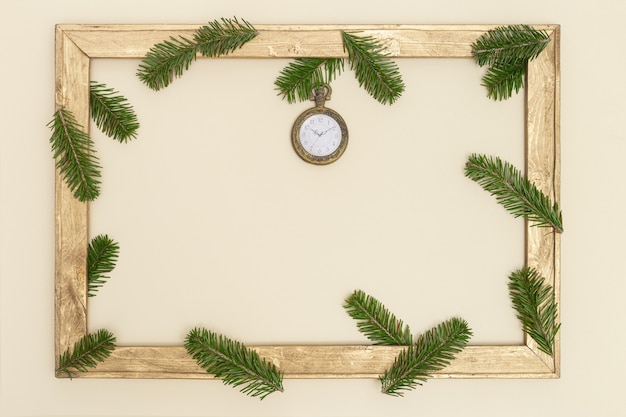 Vieux cadre en bois avec des branches de sapin vert et montre de poche vintage 10 heures