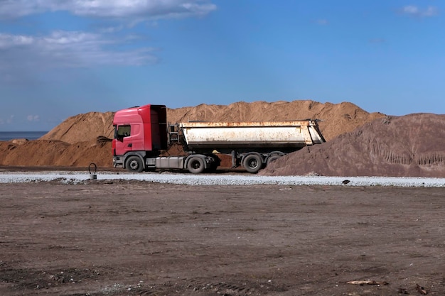 Vieux camion près du tas de sable sur le chantier de construction de la route. grand vieux concept de construction de benne basculante