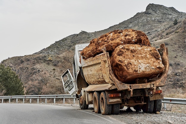 Un vieux camion transportant une énorme pierre à l'arrière est tombé en panne sur une route de montagne