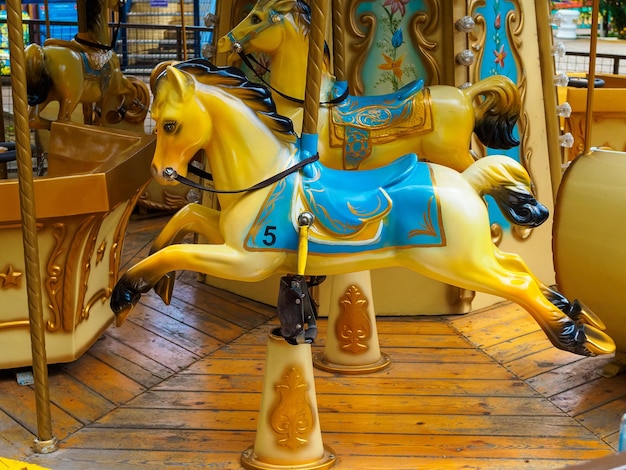 Vieux carrousel en parc avec les chevaux jaunes