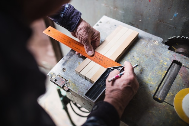 Vieux charpentier prenant la mesure d'une planche en bois