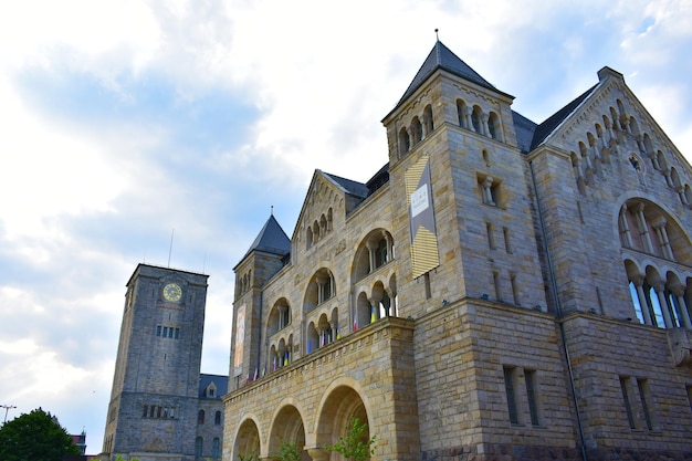 Photo vieux château en briques grises avec des tours, de hautes fenêtres et des arches avec un toit bleu, pologne poznan