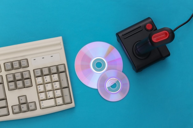 Photo vieux clavier et joystick, cd sur fond bleu. jeu rétro. jeu vidéo. années 80. vue de dessus. mise à plat