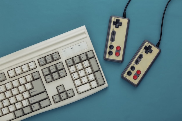 Photo vieux clavier et manettes de jeu à l'ancienne sur fond bleu. jeu rétro. années 80. vue de dessus. mise à plat