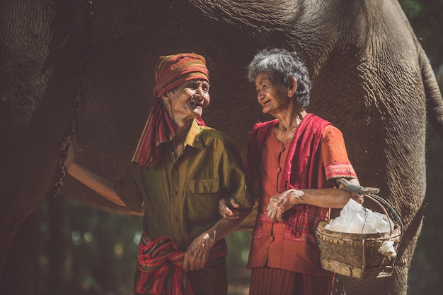 Vieux couple marchant avec leur éléphant dans la jungle, en Thaïlande