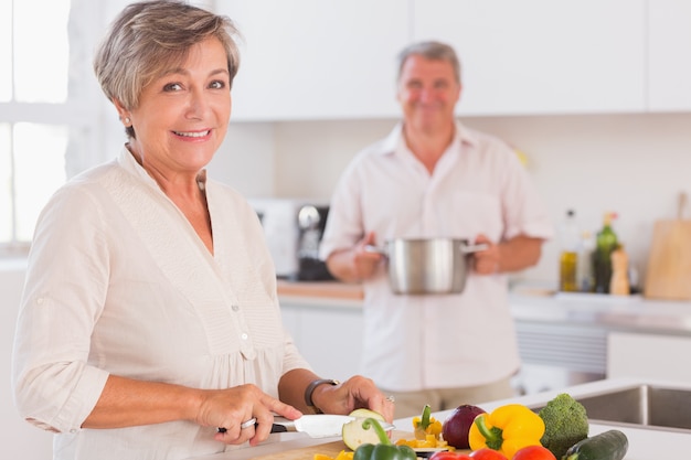 Vieux couple souriant préparant la nourriture