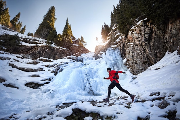 Vieux coureur près d'une cascade gelée en hiver