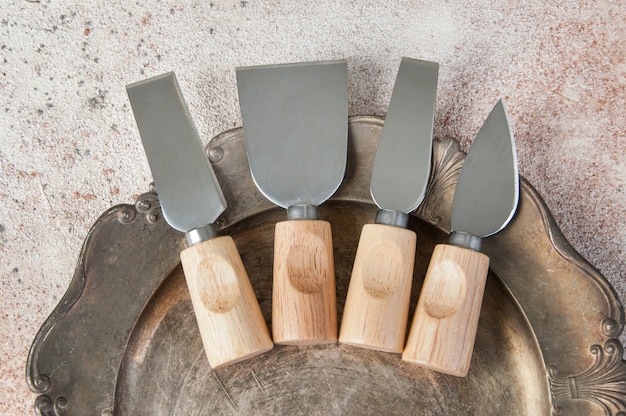 Vieux couteaux à fromage sur plat métal vintage