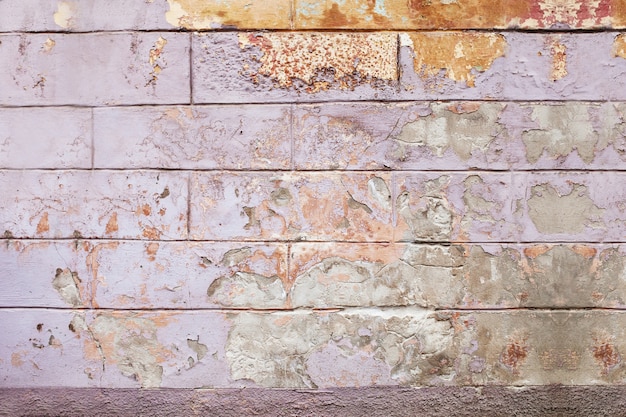 Vieux fond de mur fissuré, la texture de la peinture lilas et orange s'écaille