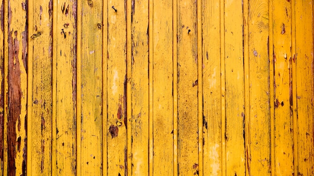 Vieux fond de texture bois jaune. mur en bois peint. Fond jaune. Clôture lumineuse faite de planches verticales. La texture d'une planche de bois peut être utilisée pour l'arrière-plan. Un peu de peinture craquelée.