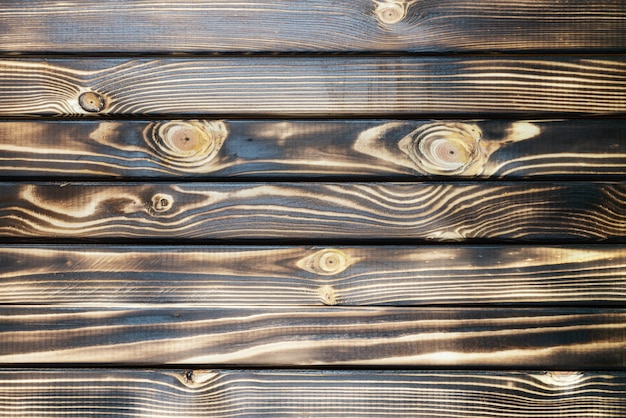 Vieux fond de texture brun foncé de planche de bois brûlé avec des planches horizontales. Vue rapprochée à plat.