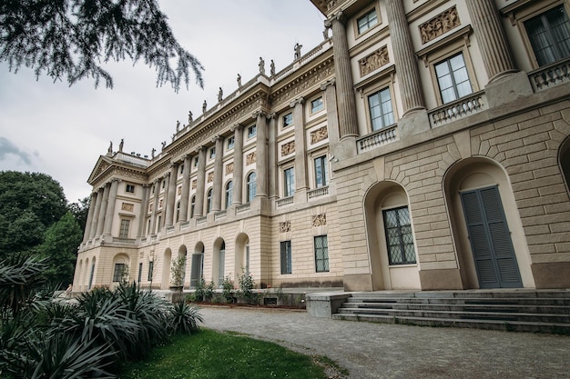 Vieux grand bâtiment sur l'herbe verte et le ciel nuageux