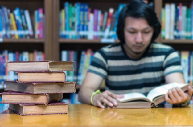 vieux livre sur le bureau dans la bibliothèque avec l&#39;homme lisant le fond du livre