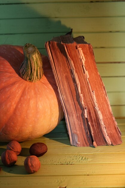 Vieux livre citrouille et bougie sur table en bois