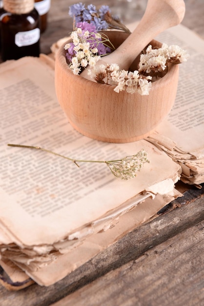 Vieux livre avec des fleurs sèches dans du mortier et des bouteilles sur la table se bouchent
