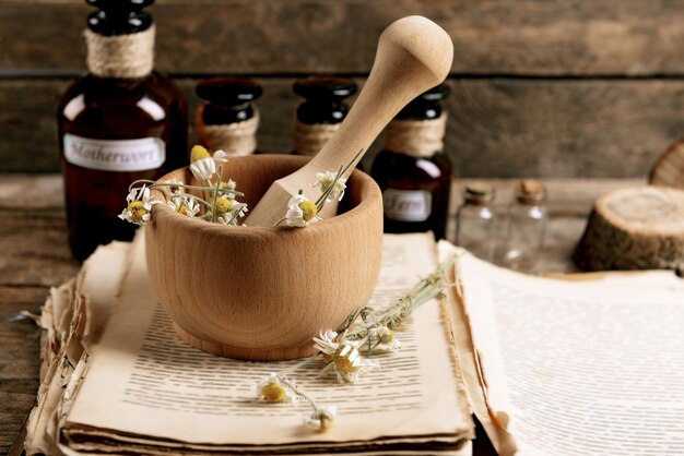 Vieux livre avec des fleurs sèches dans le mortier et des bouteilles sur la table en gros plan