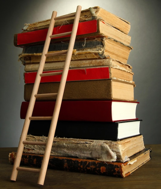 Vieux livres et échelle en bois sur fond gris