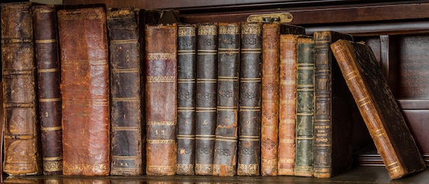 Vieux livres placés sur une étagère en bois