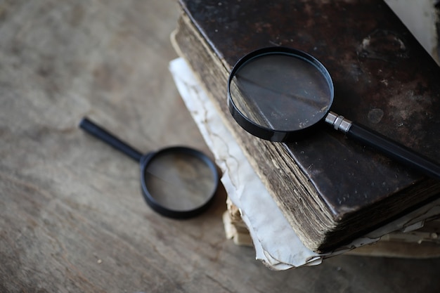 Vieux livres sur une table en bois et une loupe en verre