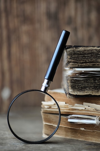 Vieux livres sur une table en bois et une loupe en verre