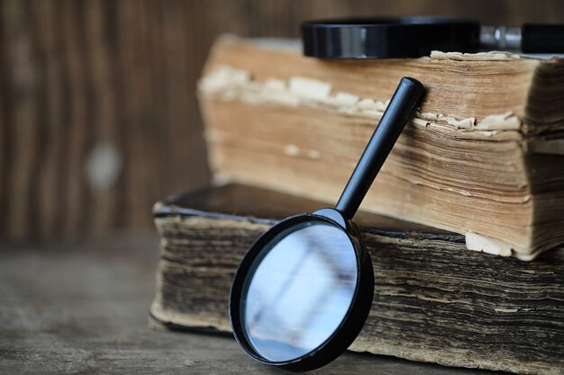 Vieux livres sur une table en bois et une loupe en verre