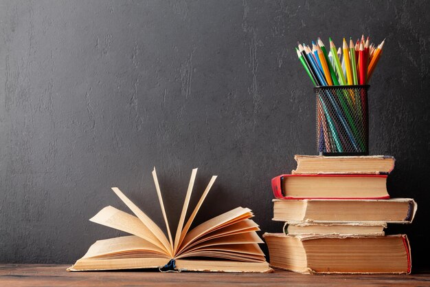 Vieux livres sur table en bois et tableau noir