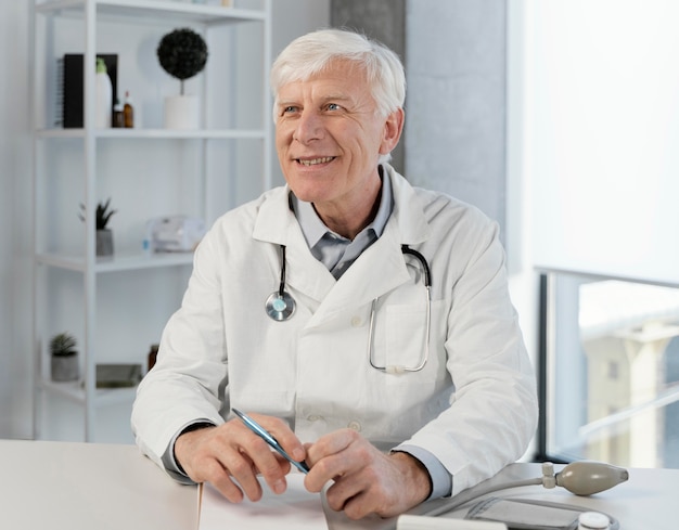 Photo vieux médecin de sexe masculin dans son bureau