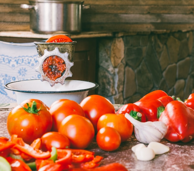 Vieux moulin vintage et tranches de tomates fraîches, poivron rouge et ail sur la table