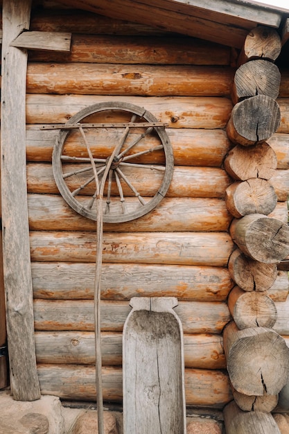 Un vieux mur en bois d'une maison du village et d'anciens outils de roues de charrette, etc.