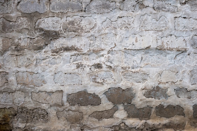 Vieux mur de brique cahoteux peint en couleur blanche