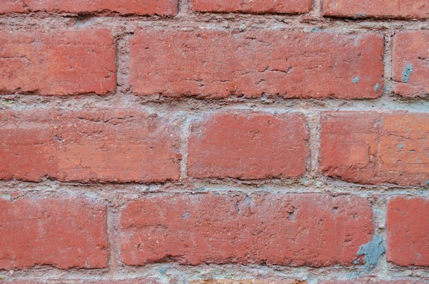 Le vieux mur de briques est rouge.