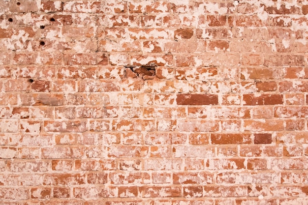 Vieux mur de briques orange avec des fissures sur les briques. mur vintage minable