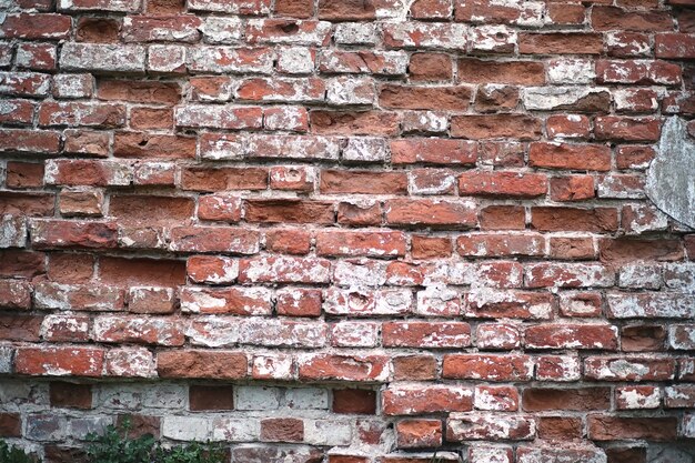 Vieux mur de briques rouges avec une fissure et des traces de peinture