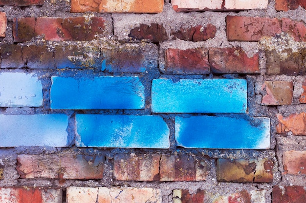 vieux mur de briques rouges et quelques briques modernes partiellement peintes en bleu