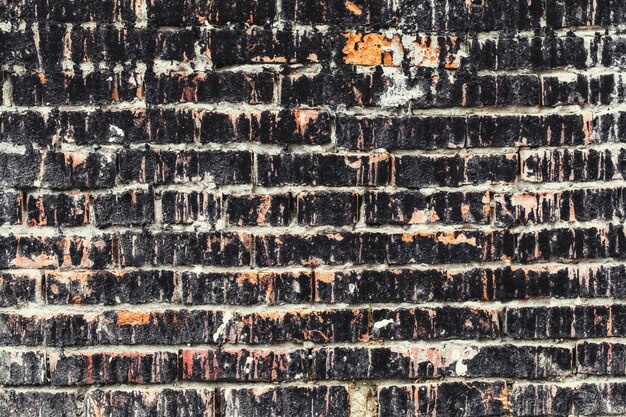 Vieux mur de briques sombres taché par les intempéries, mur de grunge de texture