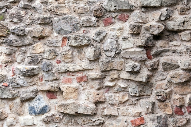 Vieux mur fait de grosses pierres et de briques cassées