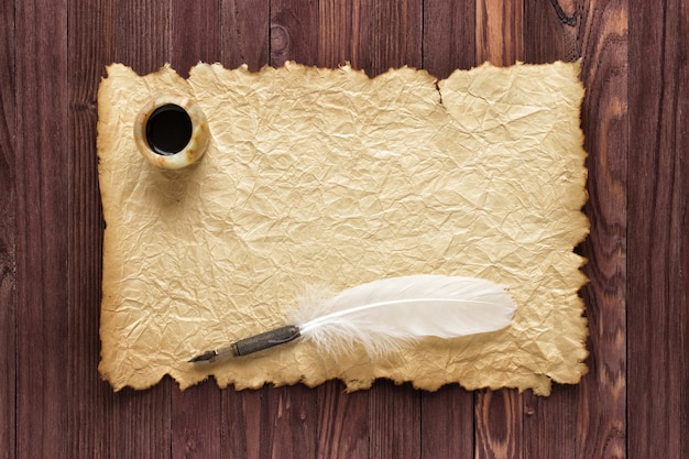 Vieux papier et encrier avec plume d'oie sur fond de bois