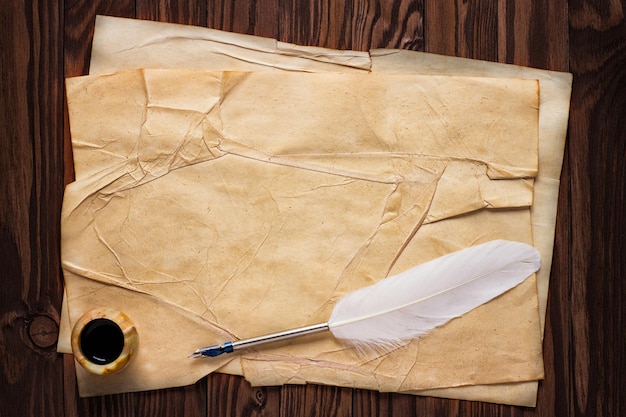 Vieux papier et encrier avec plume d'oie sur un fond de bois