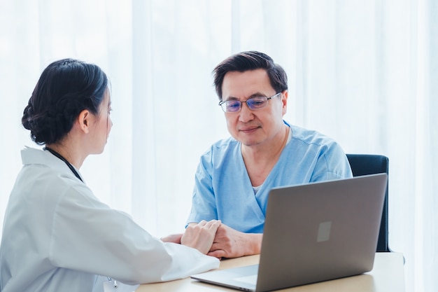 Vieux patients hommes discutant avec des femmes médecins dans le bureau de la clinique