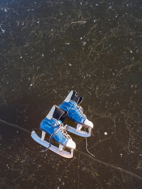 Vieux patins bleus se trouvent sur la glace d'un lac gelé au petit matin ensoleillé en hiver