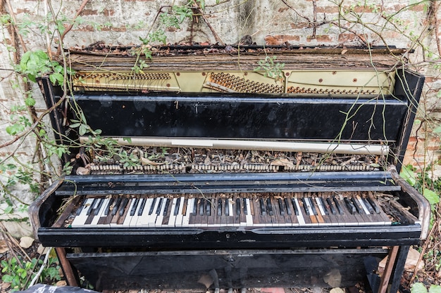 Vieux piano avec mur de béton et feuille